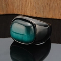 Macro detail of wide gunmetal band ring with large oval green cat eye stone - Black Base Green Gemstone