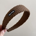 Detail shot of chunky knit brown headband with a black lettered logo patch - Letter Patch Knitted Headband - Coffee