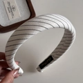 Détail d'un serre-tête en tissu rayé doux avec points diagonaux et étiquette de marque tissée - Serre-tête Rembourré en Tissu à Rayures / Blanc Cassé