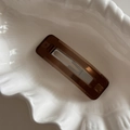 Detailed macro view of a brown rectangular resin hair clip on a white shell plate - Brown Rectangular