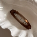 Macro shot of a vintage amber brown oval hair clip on a white decorative shell tray - Tea Brown Oval