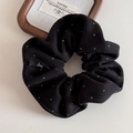 Dettaglio ravvicinato di un elastico per capelli nero a pois con etichetta logo - Nero