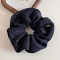 Gros plan sur chouchou bleu marine à pois avec détail d'étiquette logo petit nœud - Bleu marine