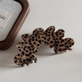 Dettaglio della molletta per capelli ondulata maculata su un vassoio di legno elegante - Stile Petalo