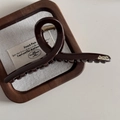 Detalle de una pinza para el cabello marrón brillante con letras doradas en bandeja de madera - Chocolate-Cruzado