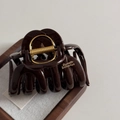 Close-up of a large chocolate brown hair claw clip with golden lettering on a wooden tray - Chocolate-Jellyfish Claw