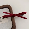 Gros plan détaillé d'une pince à cheveux nœud en daim rouge foncé avec une texture velours mate - Rouge