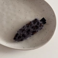 Close-up of leopard print plush hair clip on a ceramic tray for winter styling - Sparkly Leopard Gray