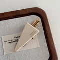 Detail der cremefarbenen Dreieck-Haarspange mit Goldmetallbasis und France-Handmade-Text - Beige