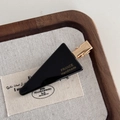 Detailansicht einer schwarzen dreieckigen Haarspange mit goldenem France Handmade Logo - Schwarz