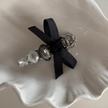 Dettaglio macro della clip per capelli con fiocco grigio, gemma e perline luccicanti - Fermaglio A Barra Con Fiocco Nero E Strass