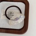 Detailed close-up of a minimalist leopard acetate hair tie with purple resin detail - Transparent White