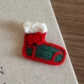 Detailed macro view of handmade knitted Christmas sock hair clip with red bow and white fur - Green Sock