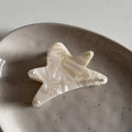 Dettaglio di una molletta per capelli a stella in acetato con venature marmorizzate - Bianco Crema
