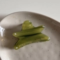 Dettaglio di una molletta per capelli a stella in acetato verde effetto marmo - Verde