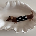 Detail einer braunen Cord-Dackel-Haarspange mit Polka-Dot-Stoff auf einem Muschelteller - Schwarz