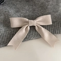 Detalle de un lazo acanalado beige sobre tejido de punto gris con puntas de cola de golondrina - Beige