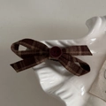 Gros plan d'une pince à cheveux vintage à carreaux marron avec bouton décoratif - Pince à Nœud Croisé