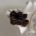 Gros plan d'une pince à cheveux à nœud écossais marron avec un bouton rétro rouge - Petite Pince à Cheveux