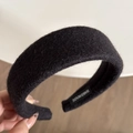 Close-up of a wide black wool fabric headband featuring a stitched handmade label - Black
