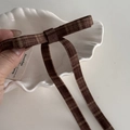 Détail d'une pince à cheveux à nœud écossais marron avec de longs rubans rétro - Pince à Nœud Streamer