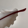 Macro di un bastoncino per capelli in acetato rosso con logo France Handmade su un piatto bianco - Rosso