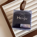 Close-up of black elastic hair ties set in a transparent square box with a brown ribbon - Twill Black