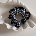 Dettaglio scrunchie a quadretti bianchi e neri con perla decorativa su vassoio bianco - Stile Perlina Rotonda