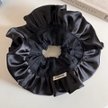 Detalle de un coletero grande de satén negro con textura plisada y etiqueta tejida - Volante Grande-Negro