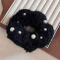 Gros plan sur un chouchou en peluche noire avec des perles élégantes et douces - Noir