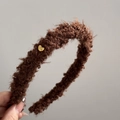Détail d'un serre-tête en peluche marron foncé avec petit cœur doré et texture douce - Créoles Bouclées En Forme De Cœur Doré - Marron
