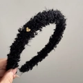Detailansicht eines schwarzen Plüsch-Haarreifens mit einem kleinen goldenen Herzanhänger - Schwarz