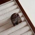 Gros plan d'une mini pince à cheveux en acétate avec motif écaille et logo doré gravé - Marron