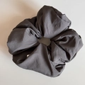 Detail view of large charcoal gray scrunchie with matte woven fabric and brand label - Scrunchie / Gray