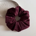 Makroaufnahme von tiefrotem Cord-Haargummi mit weicher Rippenstruktur und Vintage-Ästhetik - Vintage Samt - Rot