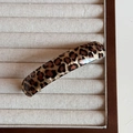 Detail einer eleganten Haarklammer mit Leopardenmuster in Braun und Schwarz auf Samt - Helles Leopardenmuster - Federclip