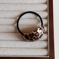 Close-up of leopard print resin geometric accessory on a black elastic hair tie - Light Leopard Print - Oval Hair Tie