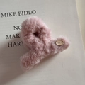 Gros plan détaillé d'une pince à cheveux en peluche rose avec étiquette ovale EGG - Petit / Rose