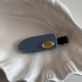 Dettaglio del fermaglio per capelli in denim blu con placca dorata su piatto bianco - Clip a Becco d'Anatra Denim Etichetta Oro - Blu Chiaro