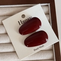 Primo piano di due fermagli per capelli in resina rosso scuro su una carta da esposizione - Clip Lega Rosso Vino - Goccia Grande
