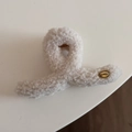 Dettaglio dell'emblema dorato e della texture di peluche crema su un grande fermaglio per capelli - Stile Incrociato con Etichetta Dorata / Bianco Sporco