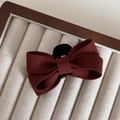 Detailed close-up of textured burgundy bow hair clip on a soft velvet jewelry tray - Gold Label Red - Small Bow Claw