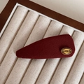 Makroaufnahme einer tiefroten Stoff-Haarspange mit goldenem Metall-Logo auf Samt - Gold-Label Rot - Wassertropfen-BB-Clip