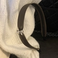 Detail of satin headband with rhinestone bow placed on white knitted fabric background - Brown