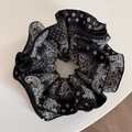 Macro detail of the paisley print and delicate overlock edge on the black fabric scrunchie - Black Paisley - Cinched Style