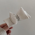 Detail view of a beige velvet bow hair clip featuring elegant double-row pearl embellishments - Artificial Pearl Bow Hair Clip / Beige