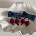 Détail des barrettes nœud en denim bleu avec boules cerises rouges dans un plateau coquille - Nœud Denim Boule Rouge - Petite Pince