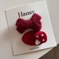 Détail d'un nœud tricoté rouge et de pinces à cheveux champignon sur carte cadeau - Champignon