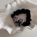 Gros plan d'un chouchou en velours noir avec pendentif cœur à fleurs et petit ruban - Chouchou à cœur / Floral Violet Café