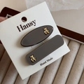 Detail of dark grey hair clips set with gold bear charms on a white display card - Khaki